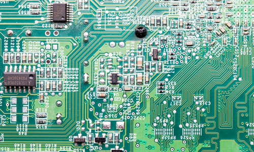 A green printed circuit board densley populated with components to accommodate smaller electronics and faster processing.
