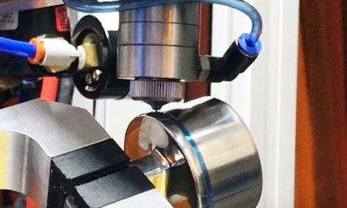 An automated dispensing system applies a light-curable SpeedMask maskant to a metal component.