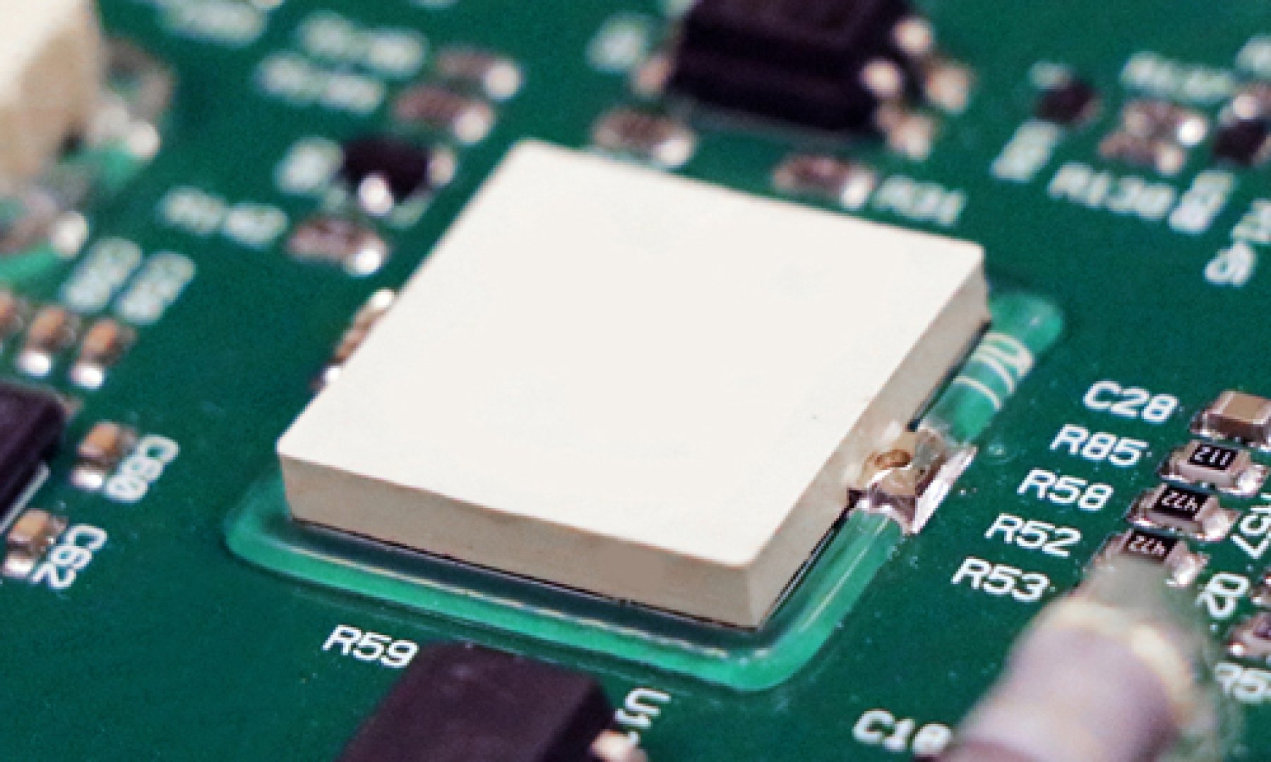 Close-up of Dymax 9310 light-curable adhesive used for edge bonding and reinforcement of components on a printed circuit board assembly.