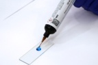 Dymax 1405M-T-UR-SC MD® Medical Adhesive dispenses blue onto plastic slide